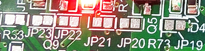 A line of solder-jumpers for MOSFETs on connector J14. From left to right: JP24, JP23, JP22, JP21, JP20, and JP19.
